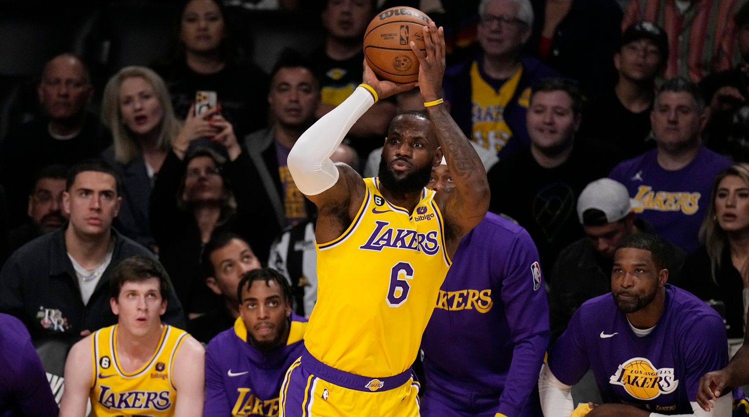 Lakers forward LeBron James shoots while several of his teammates look from the bench behind him